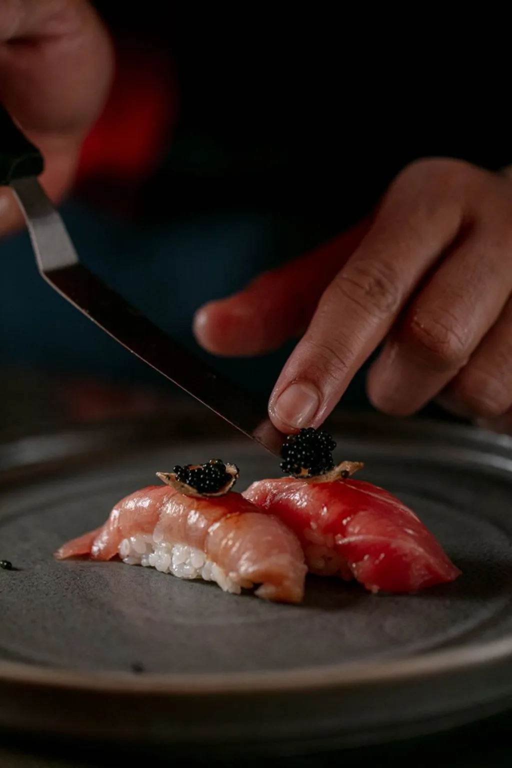 Chef finishing nigiri with caviar at the sushi counter