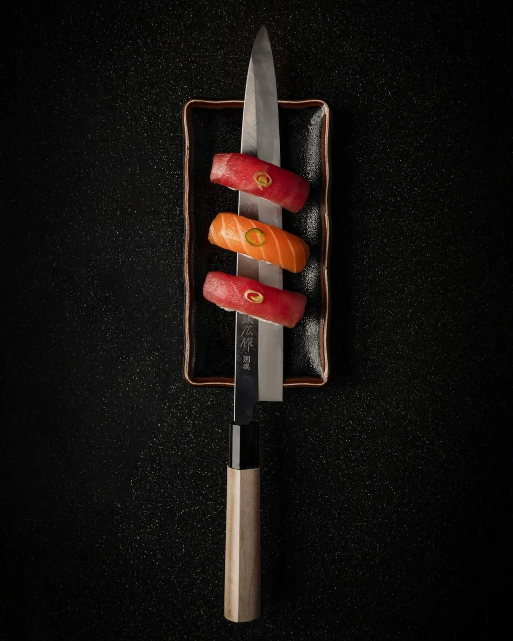 Tuna and salmon nigiri arranged over a Japanese chef knife